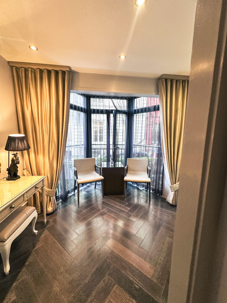 inside a luxury hotel, the athenaeum, with chairs, curtains, a table and wooden floors